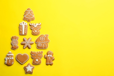 Photo of Delicious gingerbread cookies arranged in shape of Christmas tree on yellow background, flat lay. Space for text