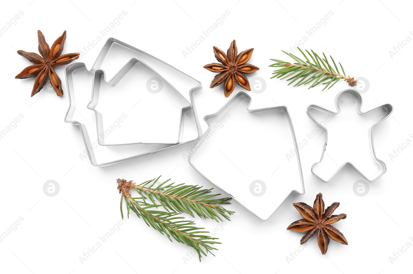 Photo of Different cookie cutters, fir branches and anise stars on white background, top view