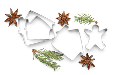 Photo of Different cookie cutters, fir branches and anise stars on white background, top view