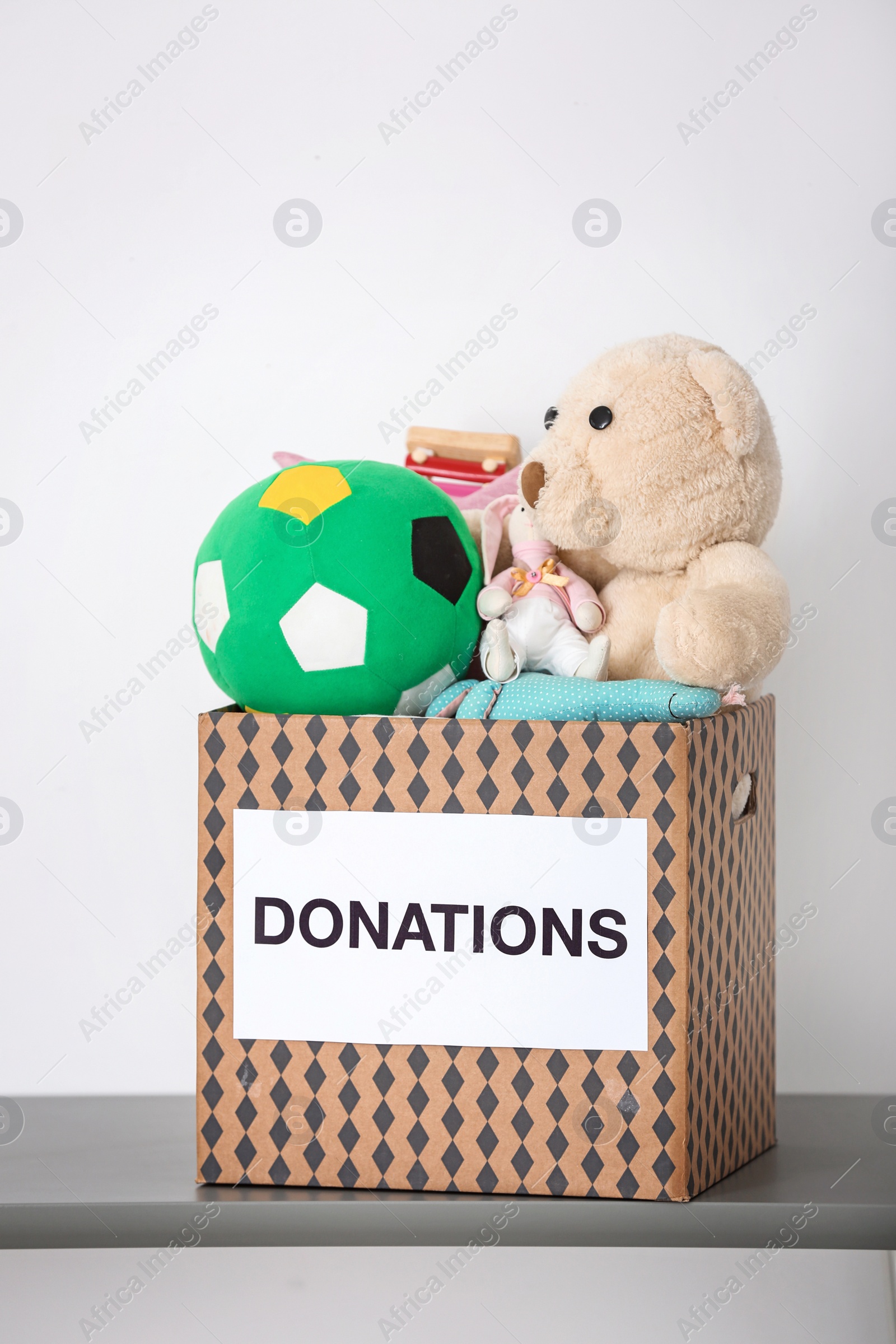 Photo of Donation box with toys on table against light background