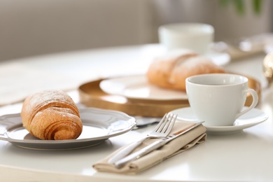 Tasty breakfast with fresh croissant and cup of coffee on table