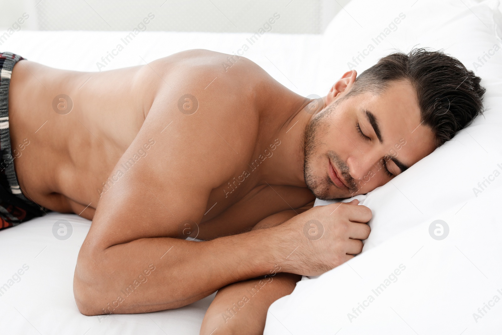 Photo of Sexy young man sleeping on bed with soft pillows at home