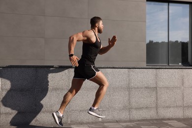 Healthy lifestyle. Young man running near building outdoors