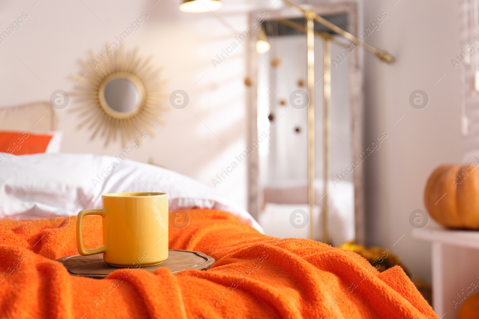 Photo of Hot drink on bed with orange blanket at home. Idea for decor in autumn colors