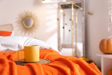 Hot drink on bed with orange blanket at home. Idea for decor in autumn colors