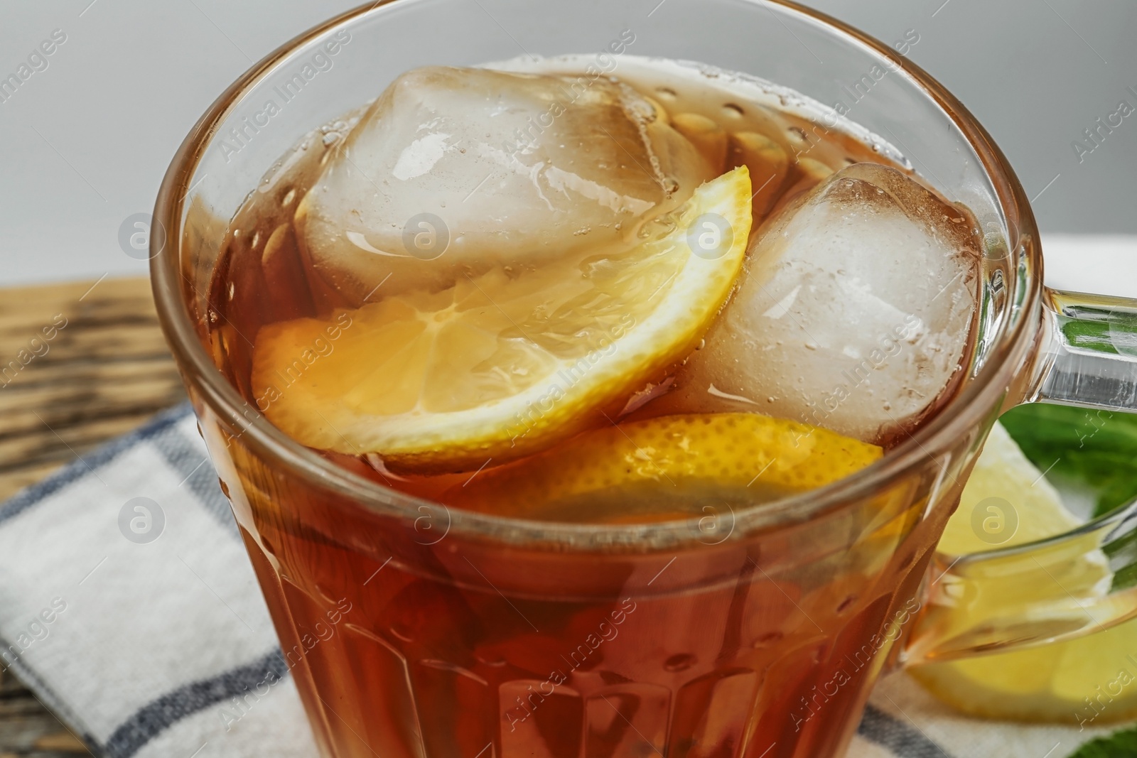 Photo of Cup of delicious iced tea on wooden table, closeup