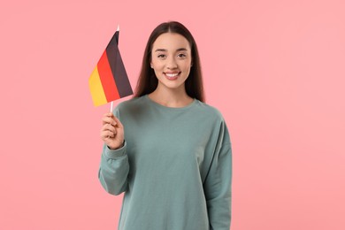 Photo of Young woman holding flag of Germany on pink background