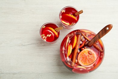 Photo of Glasses and bowl with aromatic punch drink on white wooden table, flat lay. Space for text