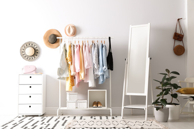 Rack with stylish women's clothes and mirror indoors. Interior design