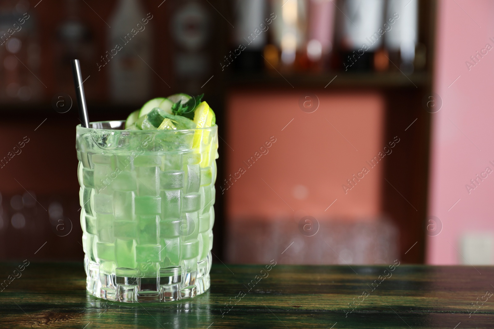 Photo of Glass of delicious cocktail with ice on table in bar