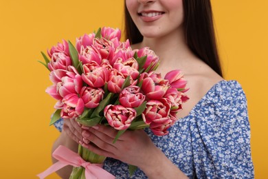 Photo of Happy woman with beautiful bouquet on orange background, closeup