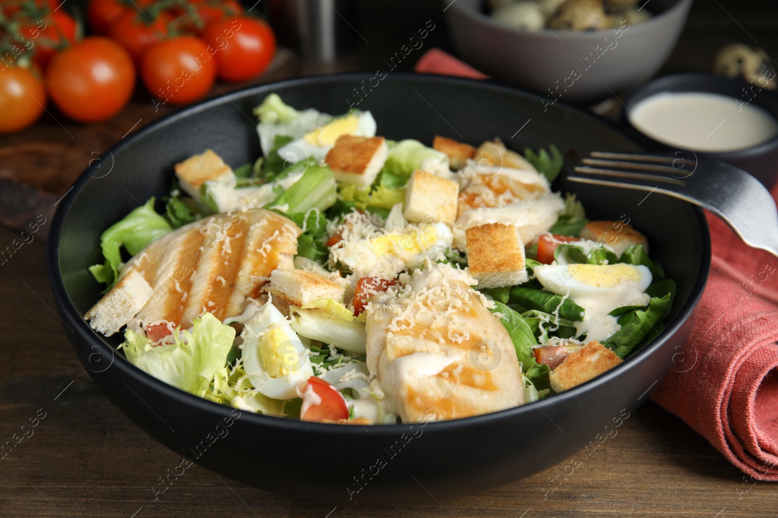 Photo of Delicious Caesar salad in bowl on wooden table, closeup