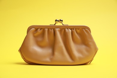 Stylish beige leather purse on yellow background