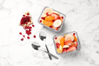 Photo of Delicious fresh fruit salad in bowls on white marble table, flat lay