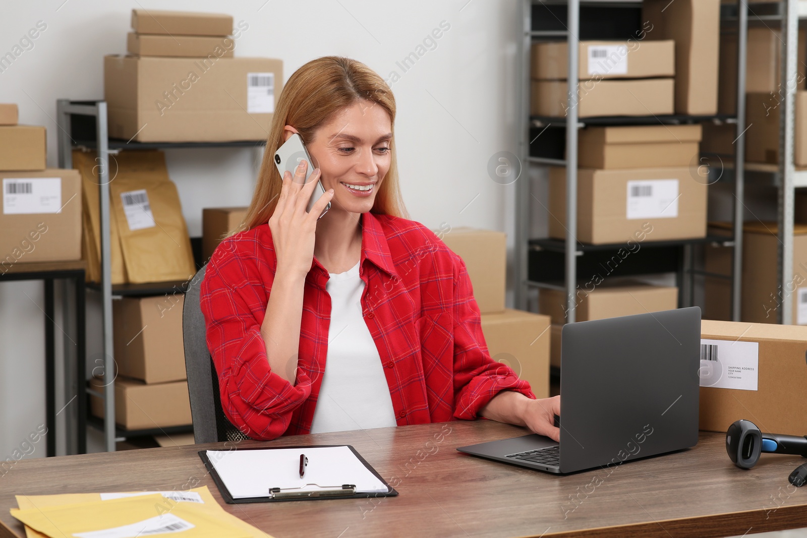 Photo of Seller talking on phone while working in office. Online store