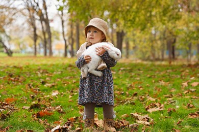 Photo of Girl walking with cute white rabbit in autumn park