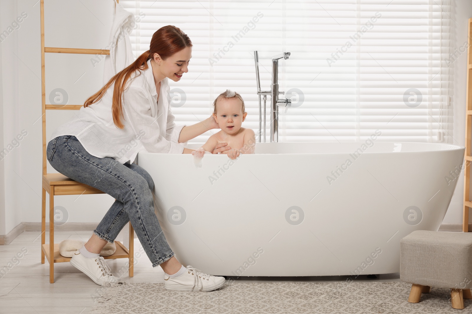 Photo of Mother washing her little baby in tub at home