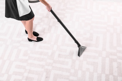 Photo of Woman cleaning carpet with vacuum cleaner, closeup. Space for text