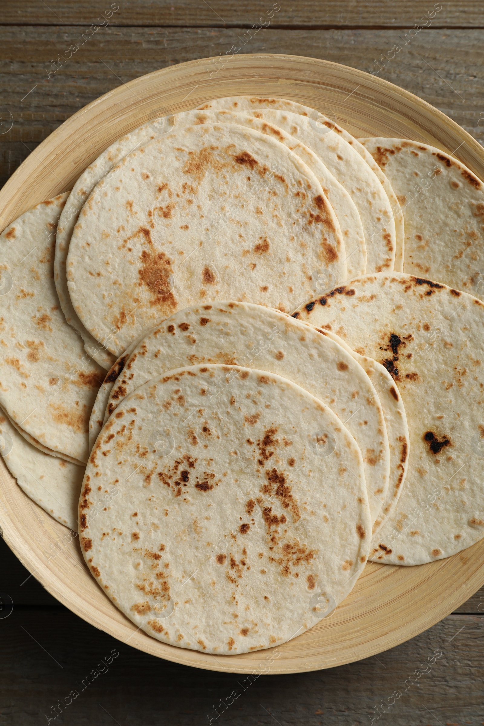 Photo of Many tasty homemade tortillas on wooden table, top view