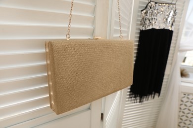 Stylish bag and dress hanging on white folding  screen, closeup. Dressing room interior