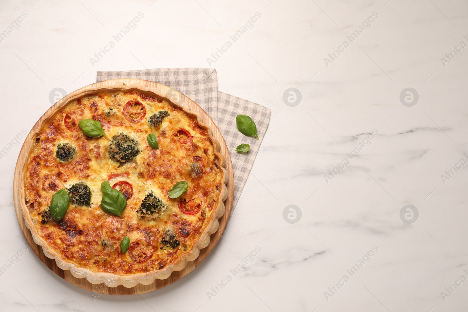 Photo of Delicious homemade vegetable quiche and basil leaves on white marble table, top view. Space for text