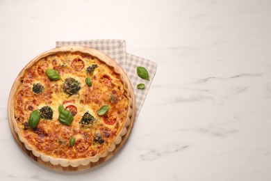 Photo of Delicious homemade vegetable quiche and basil leaves on white marble table, top view. Space for text