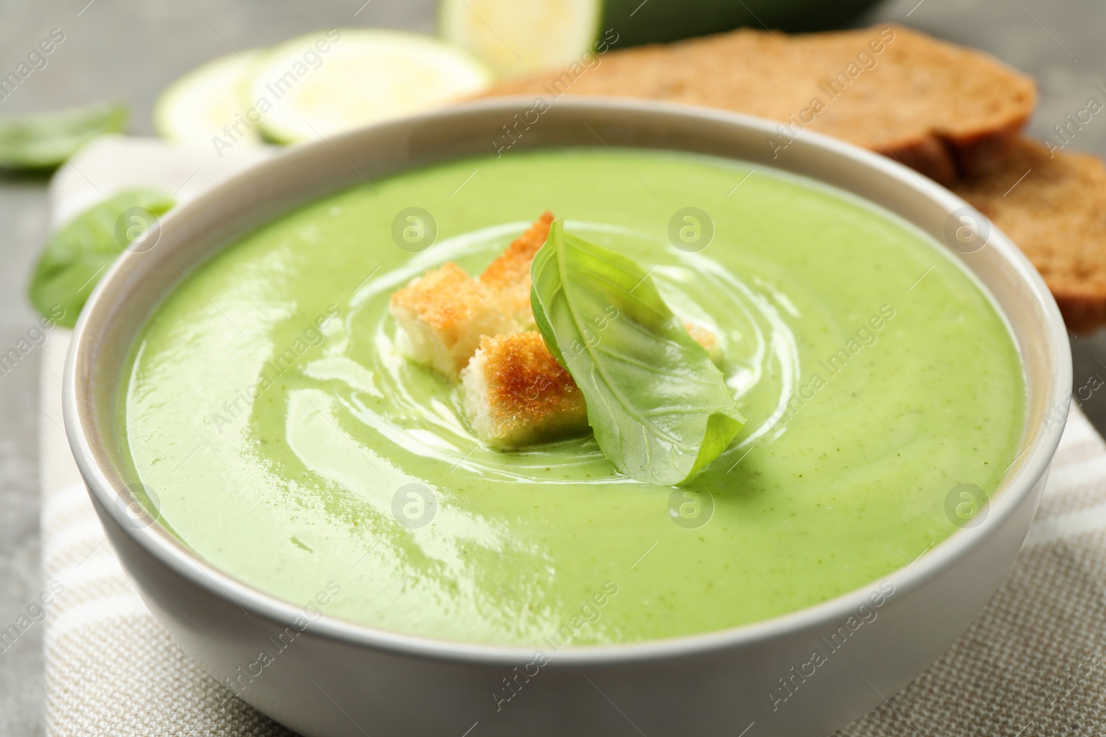 Photo of Tasty homemade zucchini cream soup in bowl on table, closeup