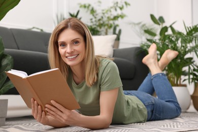 Woman reading book on floor in room with beautiful houseplants