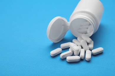 Photo of Antidepressants and medical bottle on light blue background, space for text