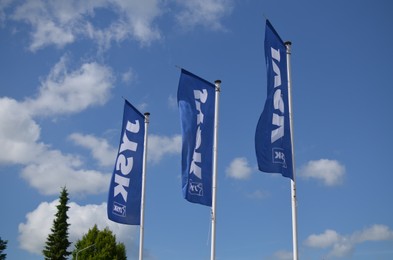 Winschoten, Netherlands - June 02, 2022: Flags of JYSK store waving under blue sky, low angle view