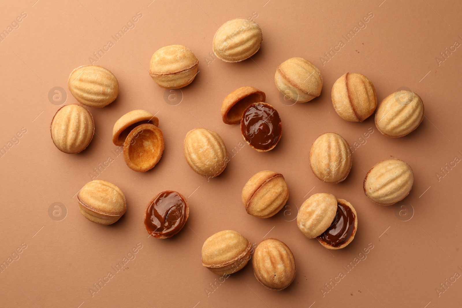 Photo of Homemade walnut shaped cookies with boiled condensed milk on pale brown background, flat lay