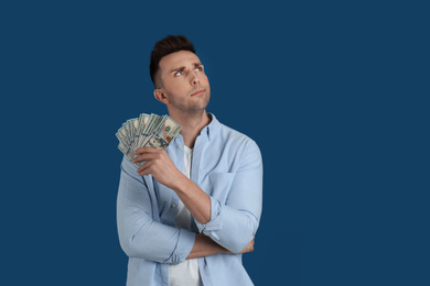 Photo of Thoughtful man with cash money on blue background