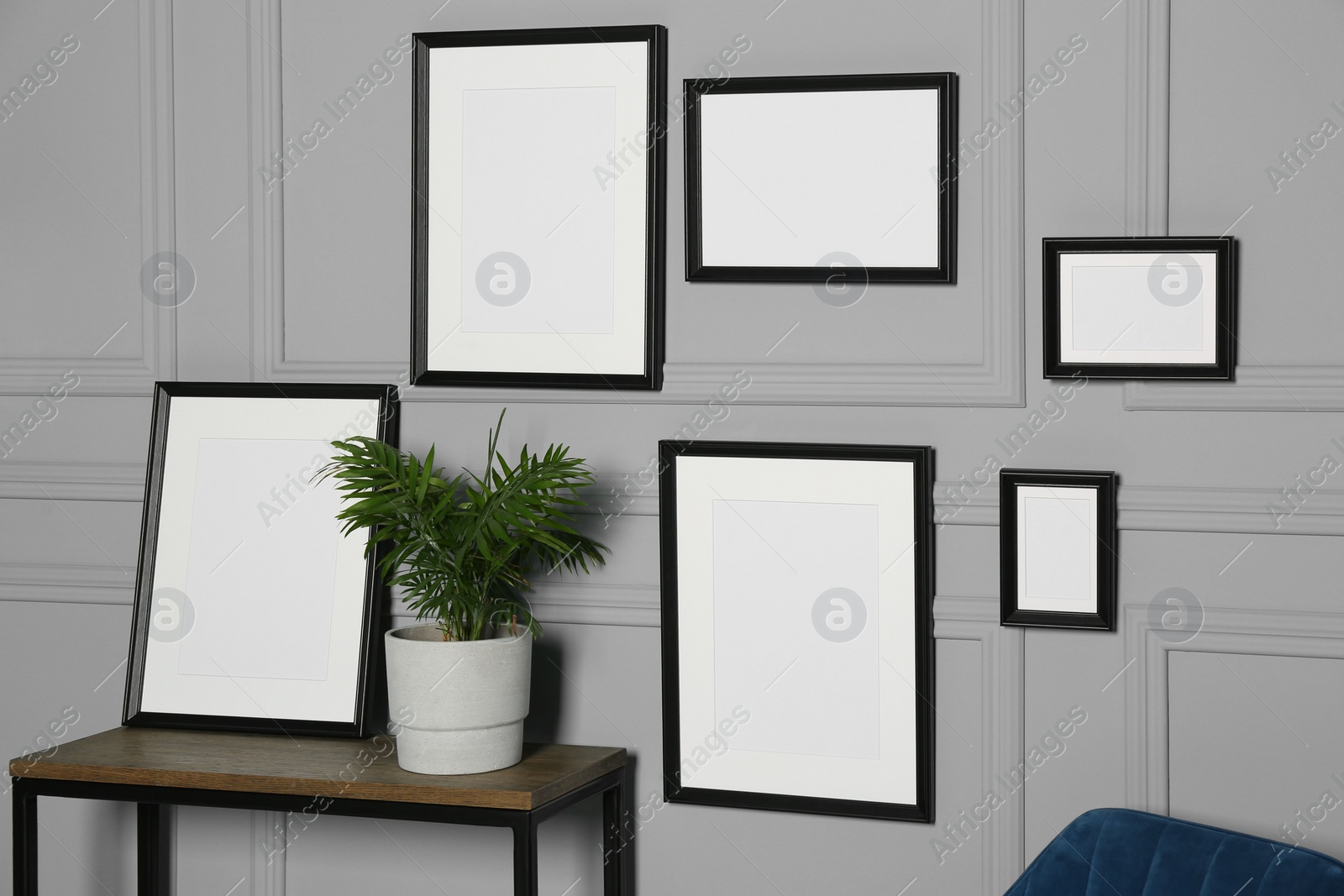 Photo of Empty frames hanging on grey wall near wooden table indoors