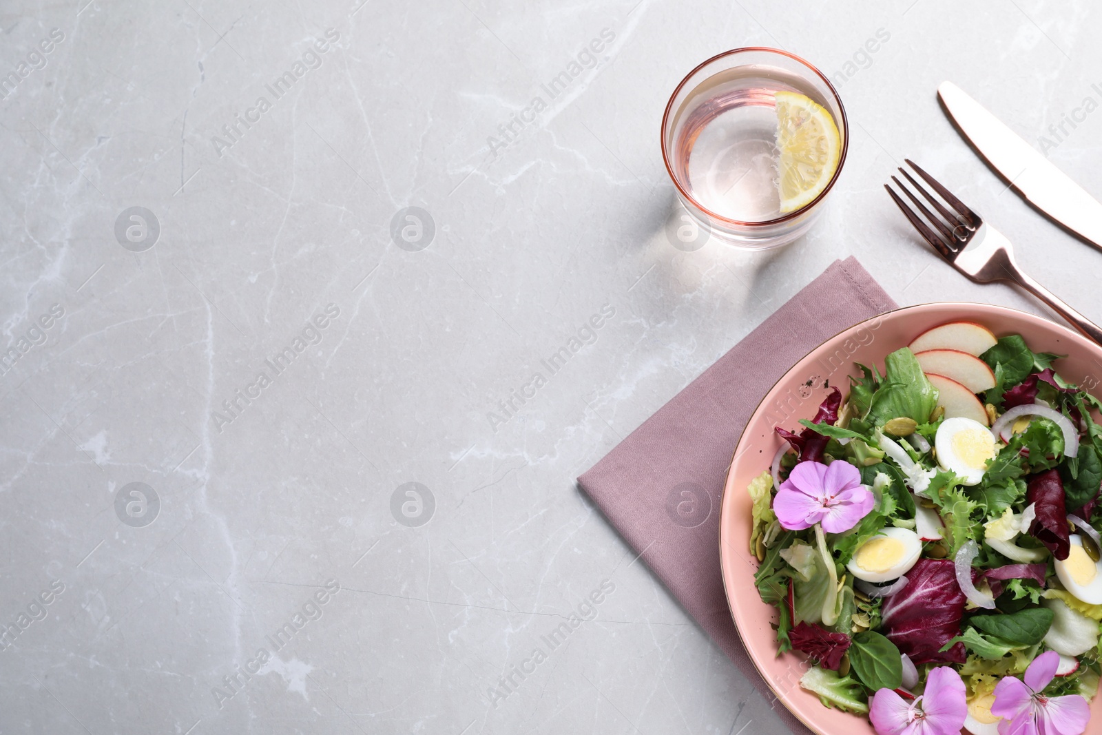 Photo of Fresh spring salad with flowers served on grey table, flat lay. Space for text