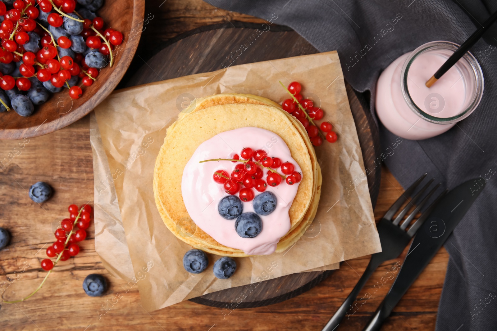 Photo of Tasty pancakes with natural yogurt, blueberries and red currants on wooden table, flat lay