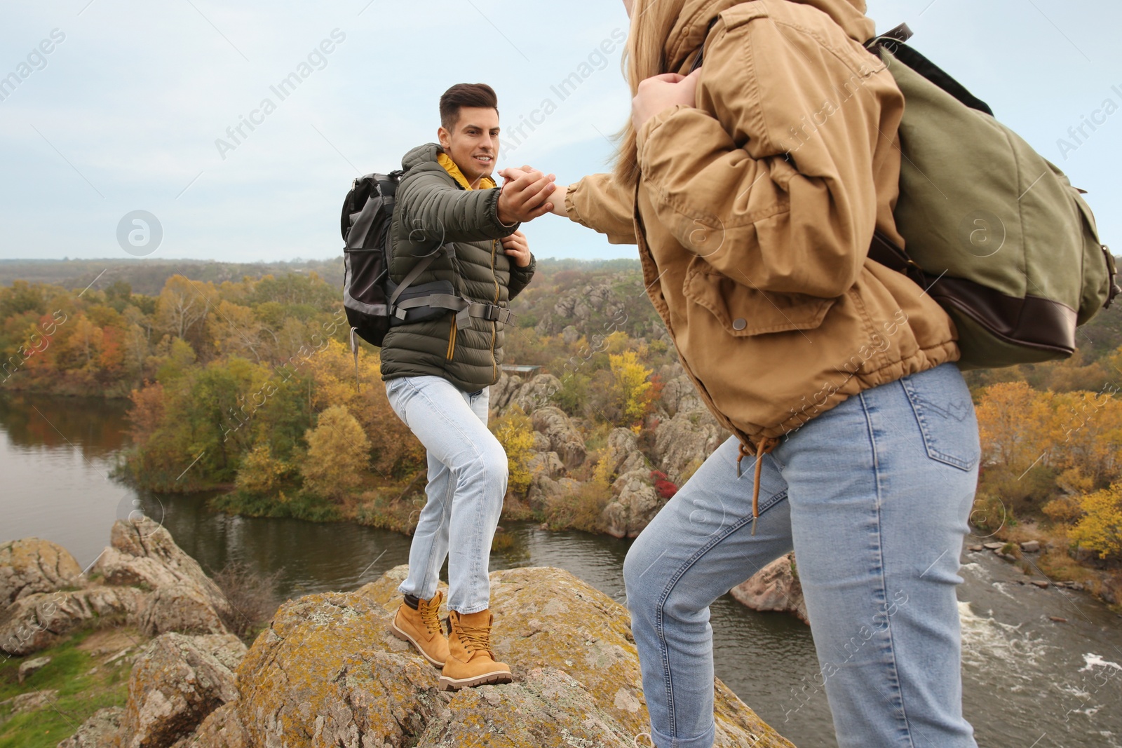 Photo of Couple of hikers with backpacks climbing up mountains