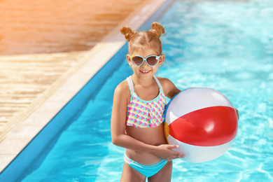 Image of Cute little girl with inflatable ball in swimming pool