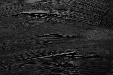 Photo of Beautiful strokes of black paint as background, closeup