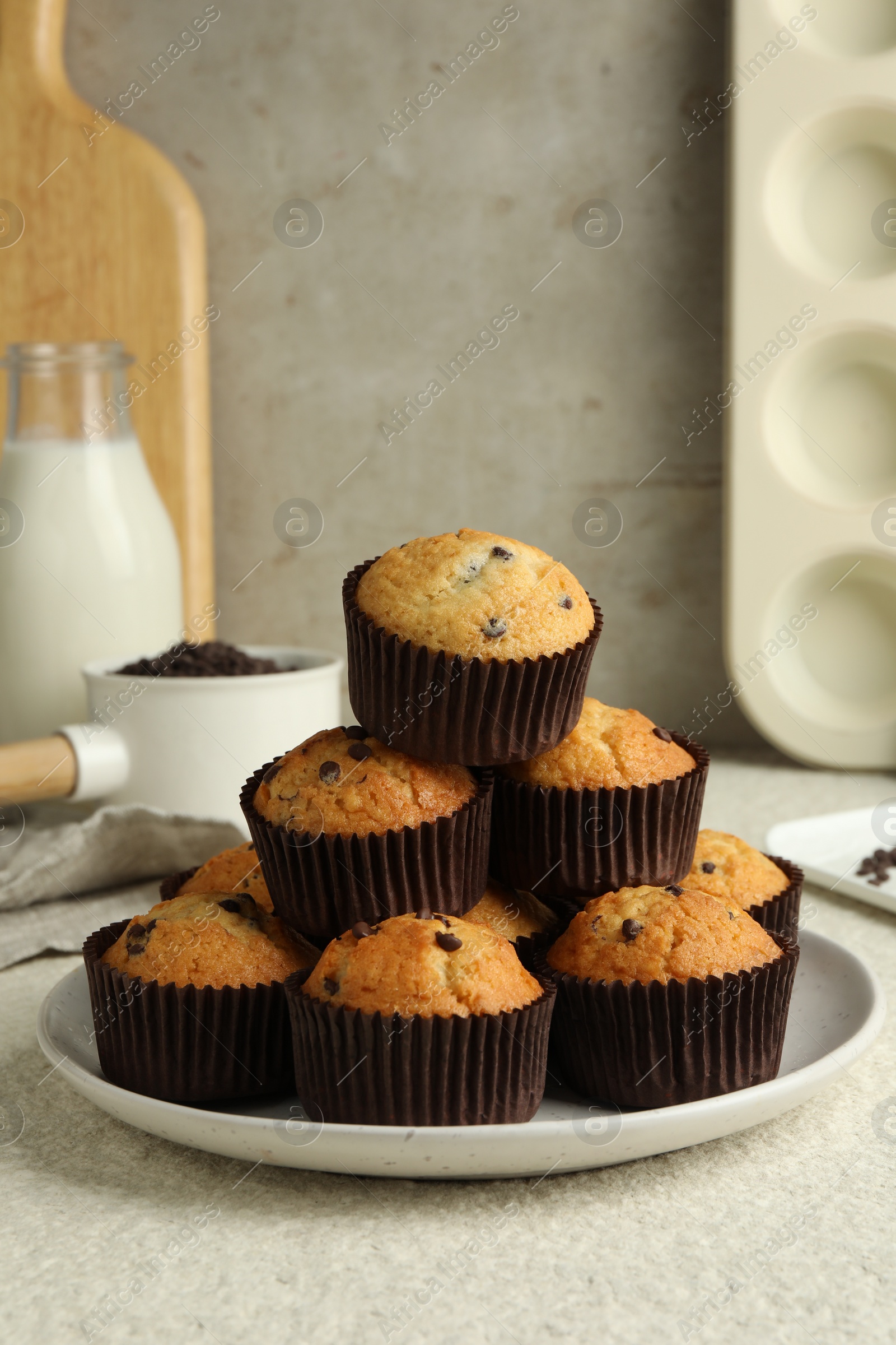 Photo of Delicious sweet muffins with chocolate chips on light textured table