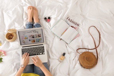 Photo of Woman and laptop with open cooking blog on bed, top view