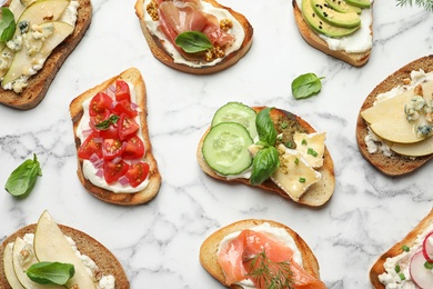 Different tasty bruschettas on marble background, flat lay