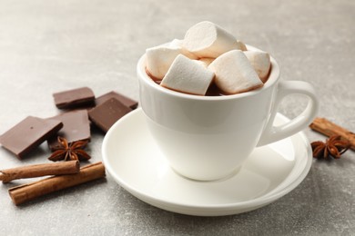 Tasty hot chocolate with marshmallows and ingredients on light grey table, closeup