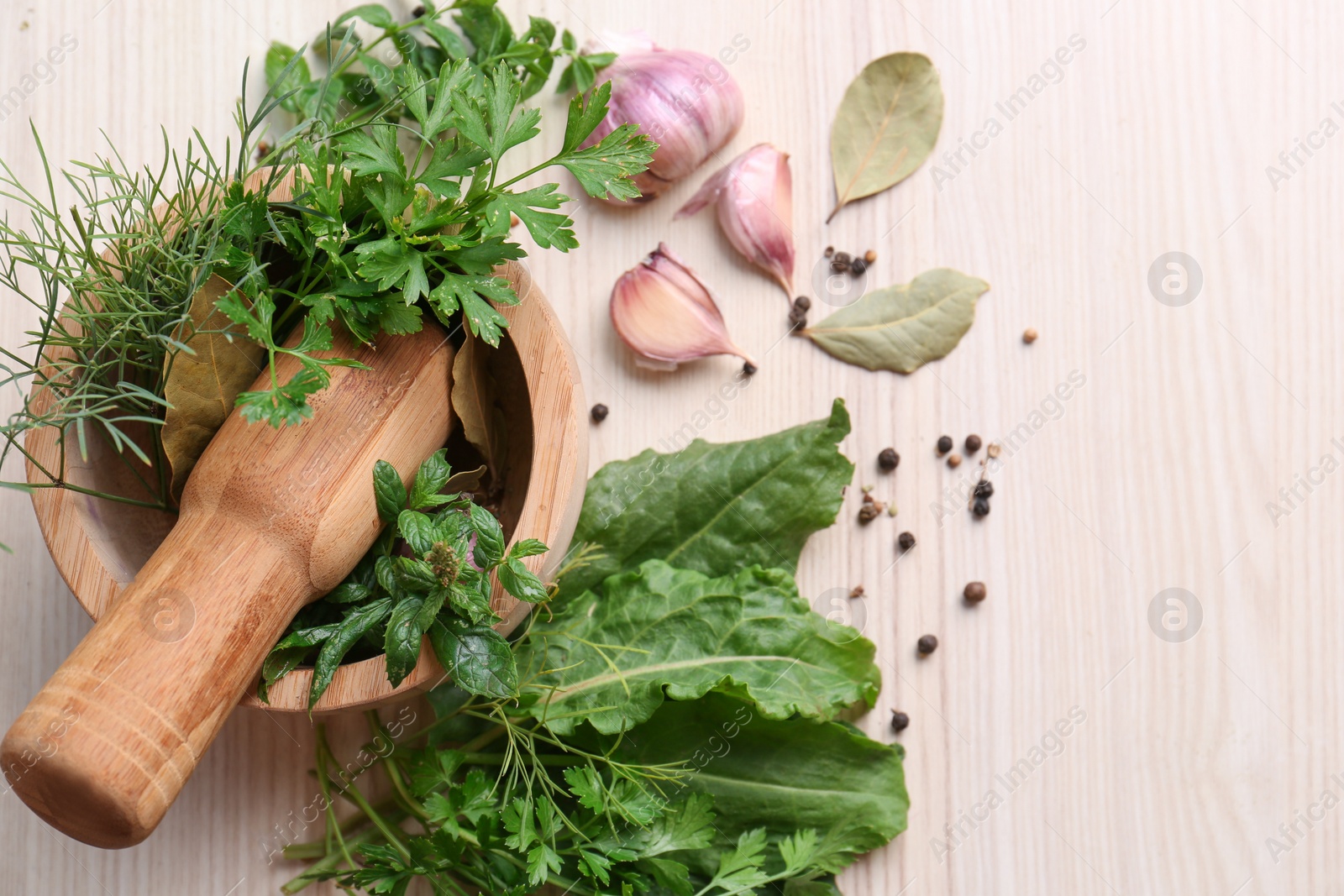 Photo of Mortar with pestle and different ingredients on wooden table, flat lay. Space for text