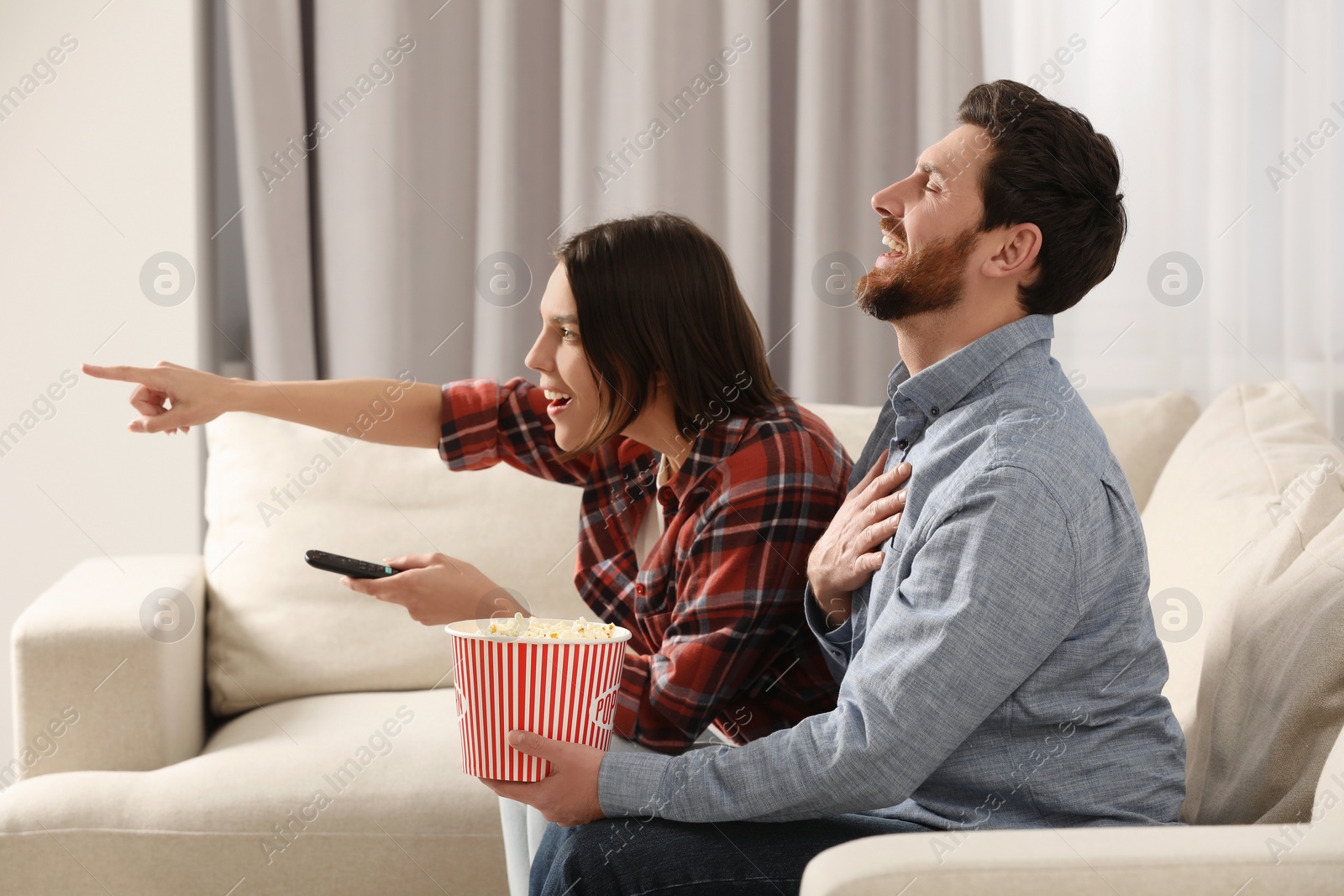 Photo of Happy couple watching TV on sofa at home