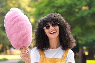 Portrait of smiling woman with cotton candy in park