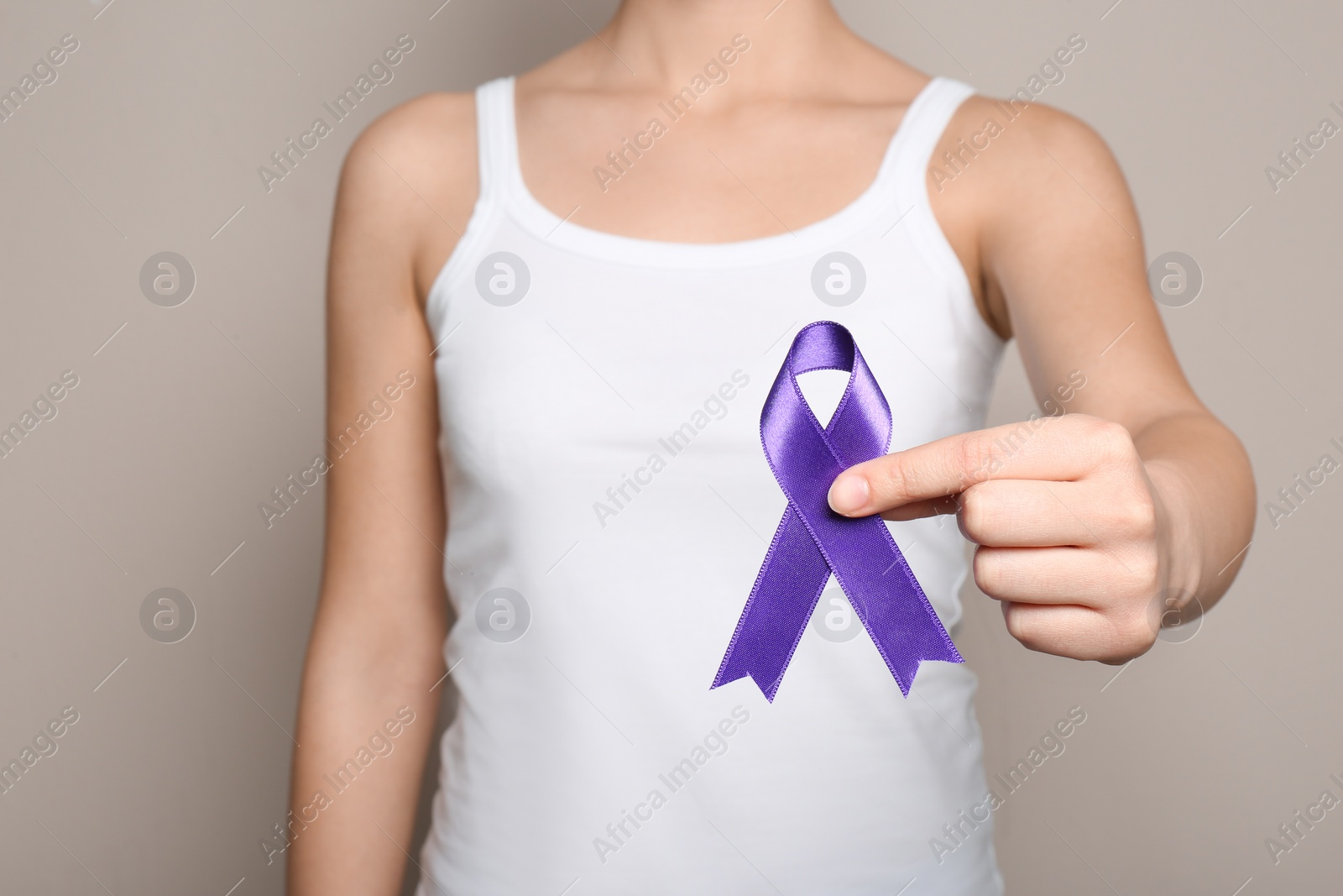 Photo of Woman holding purple ribbon on grey background, closeup. Domestic violence awareness