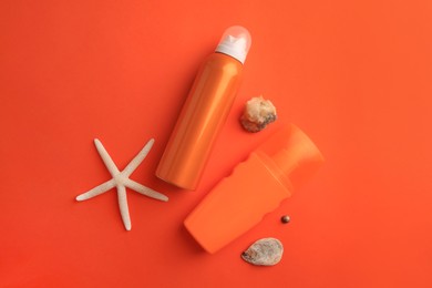 Photo of Bottles of sunscreen, seashells and starfish on coral background, flat lay