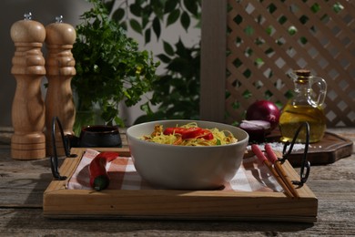 Photo of Stir-fry. Tasty noodles with vegetables and meat in bowl served on wooden table