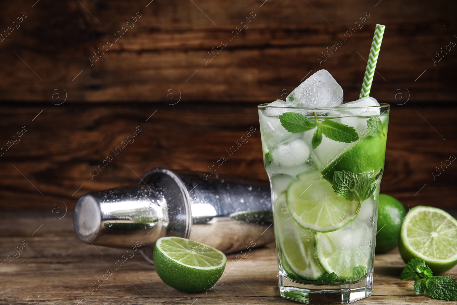 Photo of Delicious mojito and ingredients on wooden table. Space for text