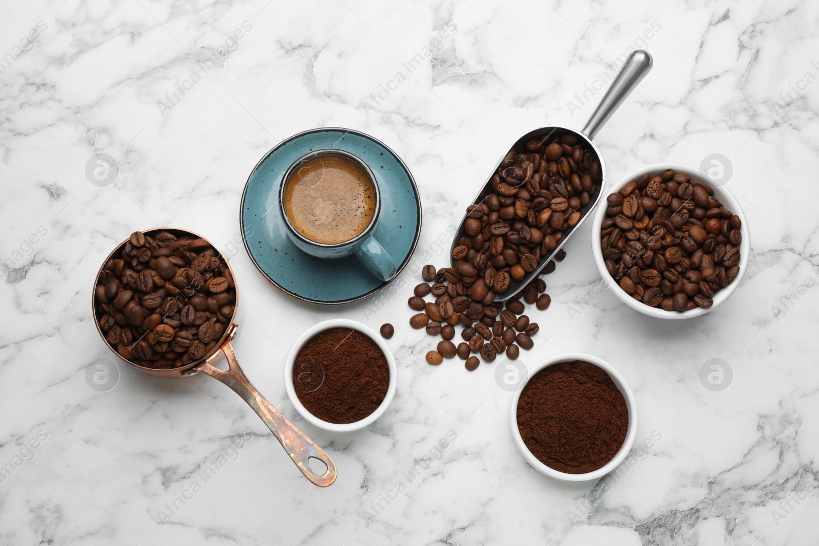 Photo of Coffee beans, powder and cup of drink on white marble table, flat lay